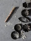 Vue de dessus de divers moules de cuisson en métal et petite brosse de cuisine sur table en marbre saupoudré de farine blanche — Photo de stock