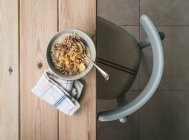 Draufsicht auf Schüssel mit frischem Haferbrei serviert mit Bananenscheiben und Löffel auf Holztisch — Stockfoto