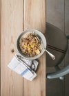 Vue du dessus du bol avec du porridge frais servi avec des tranches de banane et une cuillère sur une table en bois — Photo de stock