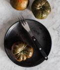 Top view of big unripe green tomatoes on black plate with metal fork and piece of cheese on plate — Stock Photo