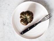 Vue de dessus de grosses tomates vertes non mûres sur plaque noire avec fourchette en métal et morceau de fromage sur plaque — Photo de stock