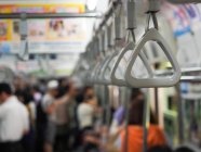 Poignées pour passagers debout dans un train de métro contemporain flou avec navetteurs au Japon — Photo de stock