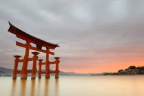 Magnifique paysage de coucher de soleil tranquille avec célèbre sanctuaire flottant sur l'eau calme avec un beau ciel nuageux en soirée d'été au Japon — Photo de stock