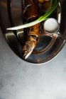 Blick von oben auf leckeren gebratenen Fisch und Kartoffeln serviert mit reifen Zwiebeln und Sahnesoße auf Metallteller im Restaurant — Stockfoto