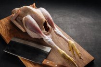 Cleaver and raw chicken on cutting board — Stock Photo