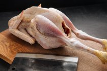 Cleaver e frango cru na placa de corte — Fotografia de Stock