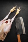 Cleaver and raw chicken on cutting board — Stock Photo