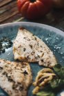 Dall'alto pesce arrosto con basilico posto su tavolo di legno squallido vicino a pomodori freschi e cipolla — Foto stock