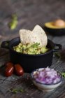 Top view of various fresh ingredients placed on lumber table near pot with yummy guacamole — Stock Photo