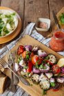 De cima de aromáticos deliciosos legumes grelhados, incluindo tomates vermelhos e pimenta com berinjelas fatiadas e cebola servida em tábua de madeira em mesa rústica com pratos caseiros — Fotografia de Stock