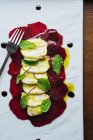 Сверху элегантный ресторанный салат с сыром моцарелла и свеклой, украшенный свежим шпинатом и соусом, подаваемый на белом подносе с вилкой — стоковое фото