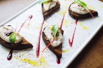 From above of delicious grilled toasts with ricotta cheese and fresh beetroot leaves garnished with sauce served on white plate in luxury restaurant — Stock Photo