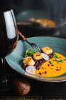 Von oben appetitanregende Delikatesse der Haute Cuisine serviert in Keramikteller mit Glas Rotwein — Stockfoto
