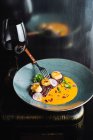 Сверху аппетитной высокой кухни деликатес подается в керамической тарелке с бокалом красного вина — стоковое фото