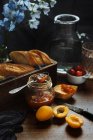 Склад свіжого багета і круасанів, поданий з ароматним солодким абрикосовим джемом на мармуровому столі — стокове фото