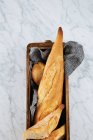 Vista superior da deliciosa baguete fatiada fresca servida em bandeja de madeira colocada na mesa de mármore — Fotografia de Stock