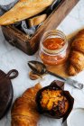 Vista dall'alto composizione di baguette fresche e croissant serviti con marmellata aromatica di albicocche dolci sul tavolo di marmo — Foto stock