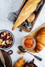 Vista dall'alto composizione di baguette fresche e croissant serviti con marmellata aromatica di albicocche dolci sul tavolo di marmo — Foto stock