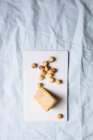 Вид зверху смачний гастрономічний блакитний сир і лісові горіхи, подані на білій дошці на мармуровому столі — стокове фото
