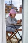 Весела маленька дитина з раковою хворобою насолоджується проведенням часу з мобільним телефоном на терасі — стокове фото