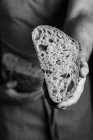 Boulanger mâle dans l'exploitation de tablier coupé en demi-pain de pain artisanal frais et sain — Photo de stock