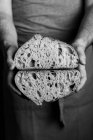 Мужчина-пекарь в фартуке, разрезанный наполовину буханкой свежего здорового ремесленного хлеба — стоковое фото