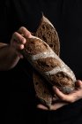 Ernte männlichen Bäcker in Schürze halten in der Hälfte Laib frisches gesundes handwerkliches Brot geschnitten — Stockfoto