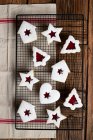 Top view of tasty homemade cookies of various shapes with red berry jam and white sugar powder placed on wooden table with utensils and decorative elements for Christmas celebration — Stock Photo