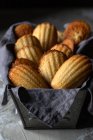 Traditionelle leckere hausgemachte Madeleine-Kekse auf schwarzem Gefäß mit Serviette auf Holztisch — Stockfoto