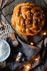 Вид зверху свіжого апетитного плетеного круглого хліба зі зморшками, розміщеними на металевій сітці на столі з різдвяними декоративними елементами — стокове фото