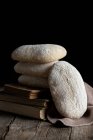 Mucchio di pane appena sfornato gustoso fatto in casa posto sul tavolo di legno accanto al pezzo tagliato sullo sfondo nero — Foto stock