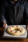 Кукурудзяний шеф-кухар в чорному фартусі тримає незапечений круглий хліб, наповнений вишнею, стоячи за дерев'яним столом — стокове фото