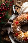 Top view of appetizing cut homemade round bread with hole decorated with sprinkles and cherry placed on wooden table with Christmas decoration — Stock Photo
