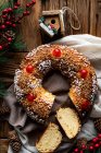Vista superior do apetitoso pão redondo caseiro cortado com furo decorado com polvilhas e cereja colocada em mesa de madeira com decoração de Natal — Fotografia de Stock