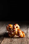Deliziosi panini allo zafferano tradizionali appena sfornati con uva passa disposti su tavolo di legno su sfondo nero — Foto stock