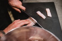 Von oben Unbekannter schneidet frische Hühnerbrust in der Nähe von Metallschüssel während eines Kochkurses in der Restaurantküche in Navarra, Spanien — Stockfoto