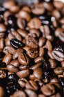 Closeup textured background with mixed black and brown fresh aromatic roasted coffee beans — Stock Photo