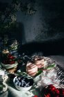 Von oben Zusammensetzung von gesunden Erdbeer-Smoothie in Gläsern auf dem Tisch mit verschiedenen frischen Beeren und Blumen im Raum mit Sonnenlicht und Schatten platziert — Stockfoto
