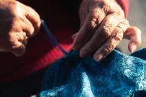 Crop elderly artisan making scarf — Stock Photo