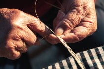 Crop senior person braiding basket — Stock Photo