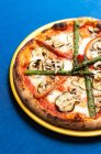 Dall'alto pizza saporita con verdure messe su piatto su tovaglia azzurra in caffè — Foto stock