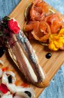 Vista superior de deliciosos sanduíches de peixe decorados com flores colocadas em tábua de madeira no restaurante — Fotografia de Stock