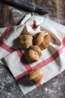 Draufsicht der Laibe frisches Brot auf einem Küchentuch auf rustikalen Holztisch mit Mehl in der Bäckerei abgedeckt platziert — Stockfoto