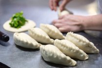 Nahaufnahme Unbekannter kneift Kuchenkruste auf Metalltisch in moderner Bäckerei — Stockfoto