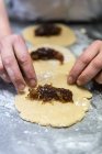 Unbekannter Koch rollt süße Marmelade in rohen Teig und kocht Teig auf Tisch in Bäckerei — Stockfoto