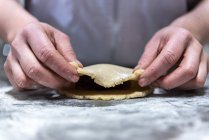 Chef méconnaissable rouler la confiture sucrée dans la pâte crue pendant la cuisson de la pâtisserie sur la table dans la boulangerie — Photo de stock