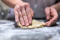 Chef irreconhecível rolando doce geleia em massa crua enquanto cozinha pastelaria na mesa na padaria — Fotografia de Stock