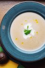 Vue de dessus de la délicieuse soupe à la crème aux cèpes garnis de feuilles de persil servies dans une assiette bleue — Photo de stock