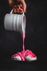 Irreconocible mano de mujer de la cosecha con frasco blanco vertiendo jarabe de fresa rosa en el postre tradicional ruso Zefir blanco casero con menta sobre fondo negro - foto de stock