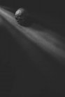 Von oben schwarz-weißer menschlicher Schädel in der Nähe von Sonnenstrahlen in dunklen Raum platziert — Stockfoto
